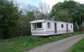 Caravan Nestled Away Amongst Trees On Edge Of Farm Yard